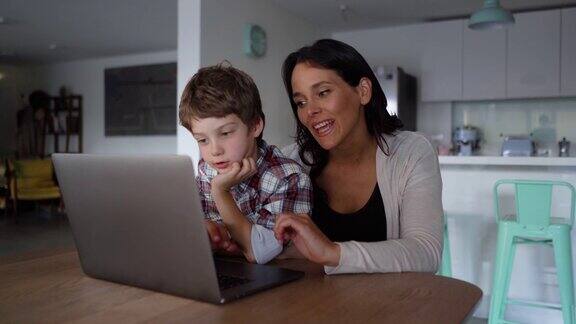 妈妈和儿子在笔记本电脑上寻找东西而妈妈解释并指着屏幕
