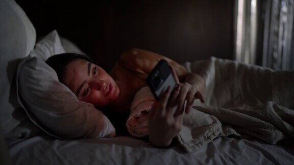 年轻女子躺在床上玩手机
