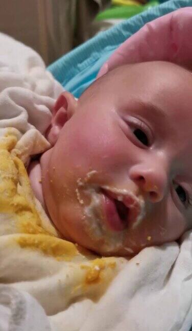 宝宝吃东西弄得一团糟三个月大的婴儿在吃晚饭看着摄像机