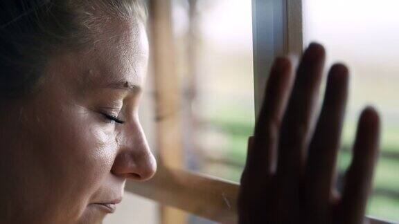 SLOMO忧郁的女子透过窗户回忆新冠肺炎封锁期间的自由