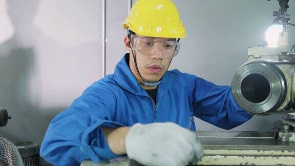 亚洲机械工人在铣床上工作技术人员在操作机器时戴上防护眼镜和安全帽以确保安全这个人小心翼翼地工作以防危险