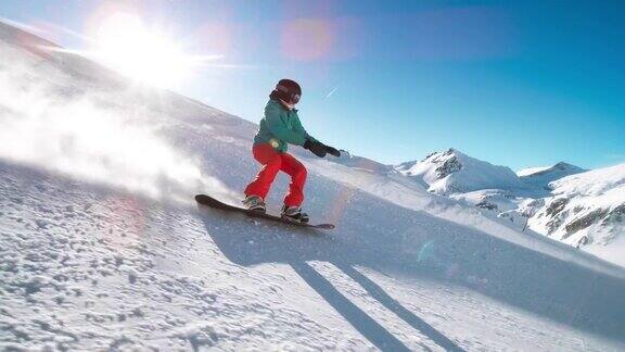 SLOMOTS女滑雪板骑下阳光明媚的山坡覆盖着新鲜的粉末
