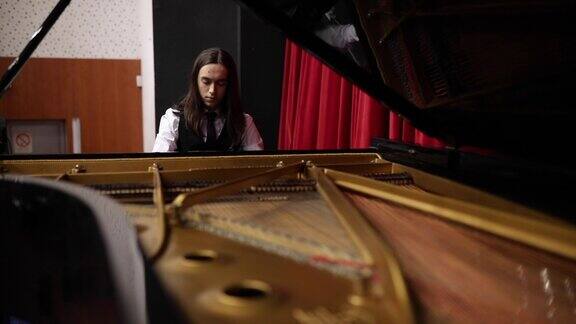 这位才华横溢的年轻钢琴家在剧院里练习他的三角钢琴演奏技巧