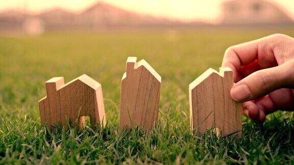 手的女人选择绿色草地上的迷你木屋模型规划购买房地产生态房子的图标概念