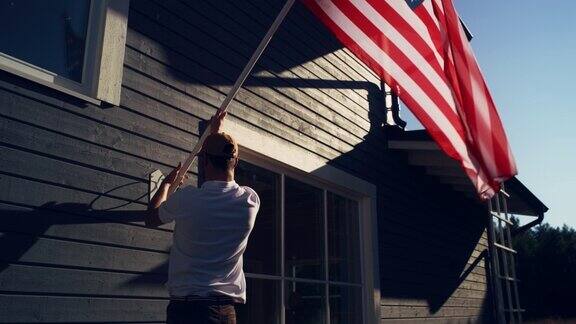 骄傲的美国房主在他的住宅悬挂美国国旗一个成年男子把国旗固定在他的房子墙上庆祝爱国主义的完美夏日