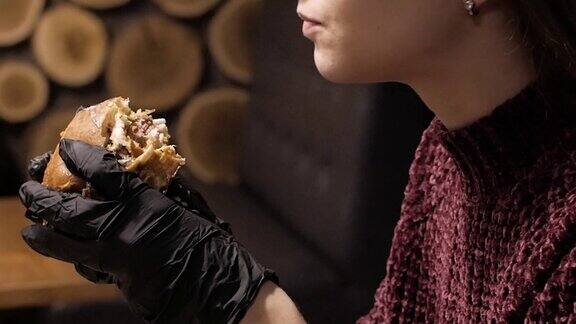 深色头发的女人在一家餐馆吃一个美味的汉堡特写