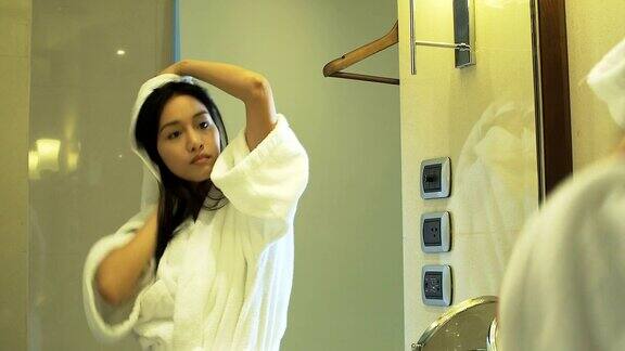美丽的亚洲女人在浴室里吹头发