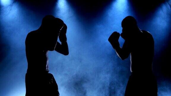 两个年轻的运动员在烟雾缭绕的拳击室剪影