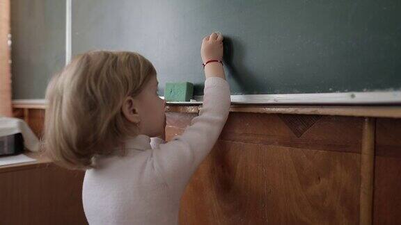 女孩在教室里用粉笔在黑板上画画教育过程