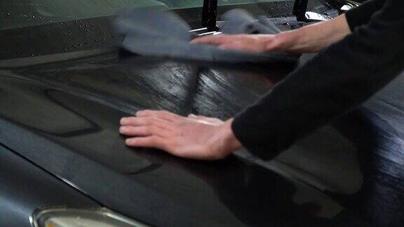 洗车工人在洗车洗车工人用干布擦拭汽车特写镜头缓慢的运动