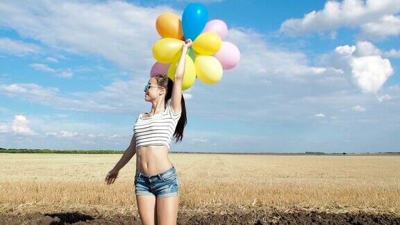 美丽的女孩在田野里拿着气球