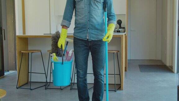 男人拿着拖把和塑料桶还有刷子手套和洗涤剂在厨房里