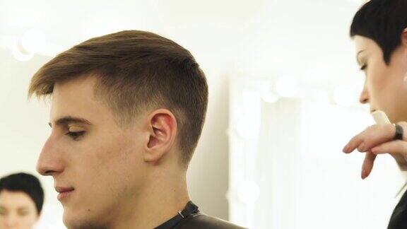 理发师在理发店用电动剃须刀理发美发师在美容室理发时喷洒水梳理湿发沙龙里的职业男性发型