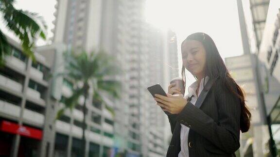 视频缓慢亚洲女人漂亮的女商人白人穿着黑色西装在用智能手机聊天在城市街道的一边