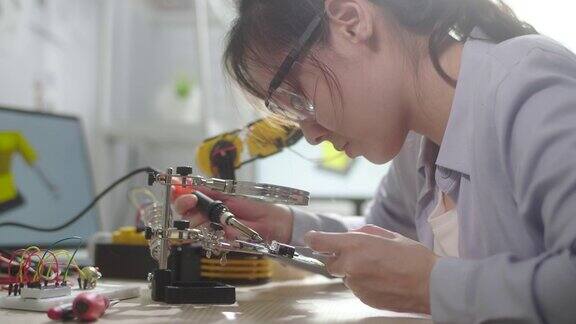 女工程师女孩正在用烙铁和电线修理电路板