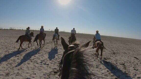 一群游猎骑手在Makgadikgadi盐田广阔的空地上慢跑的慢镜头