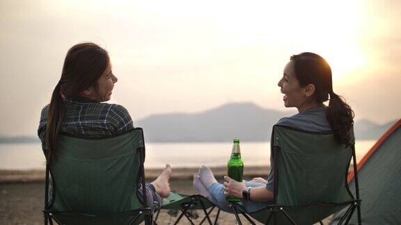 两个亚洲女人朋友一起休息在露营度假附近的湖