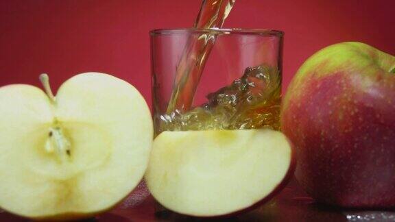 在红色背景上苹果汁倒在苹果片旁边
