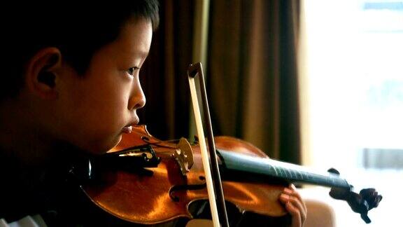 亚洲男孩在家里拉小提琴
