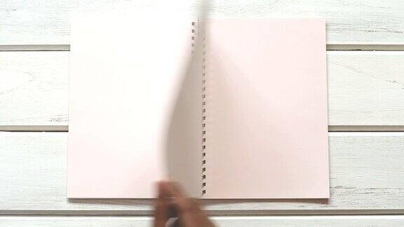 一个男手打开日记本放在白色的木桌上俯视图和头顶拍摄使用空白模板对书本进行模拟以添加任何文本内容
