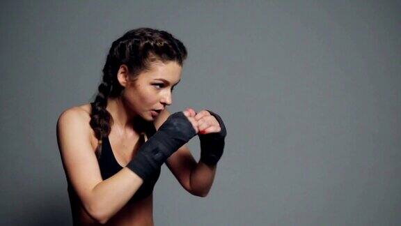 年轻女子训练与她的手包裹在拳击磁带孤立在灰色背景Slowmotion拍摄