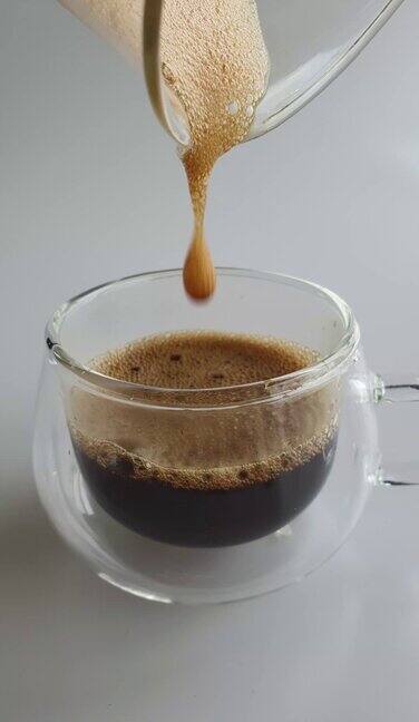 将黑咖啡倒入透明透明的杯子