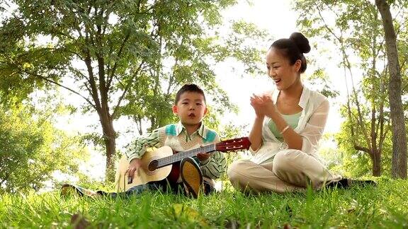 妈妈和儿子在公园里弹吉他