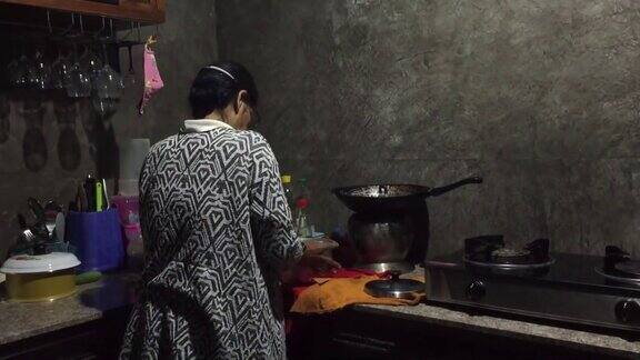 亚洲老妇人在家里的厨房里用电饭锅煮饭