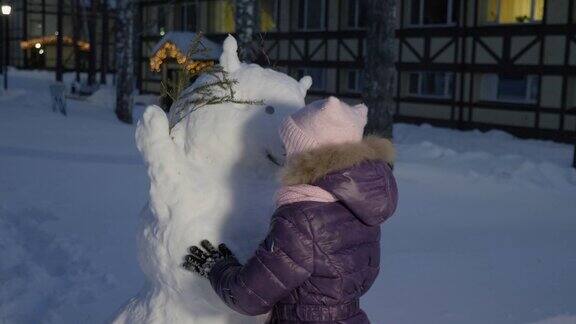 小女孩在雪地里堆雪人看着它
