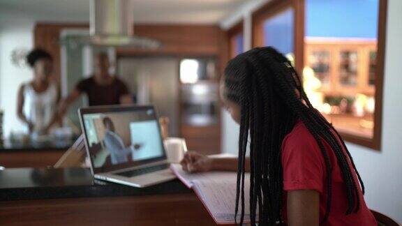 一个少女在家厨房用笔记本电脑看课