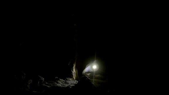 男洞穴学家在黑暗狭窄的洞穴中被抓住了脚恐怖