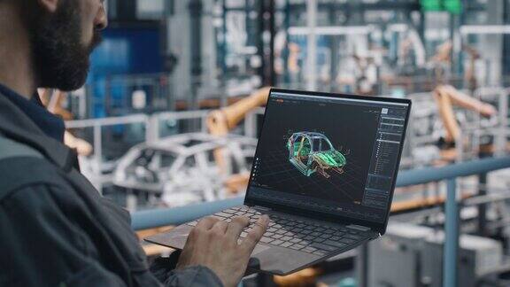 汽车工厂工程师在工作制服使用笔记本电脑与数字3DCAD车辆蓝图男汽车工业生产设备专家从事汽车生产