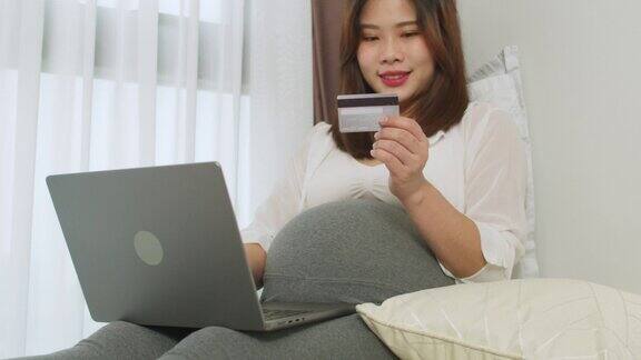 亚洲孕妇使用笔记本电脑在网上购物