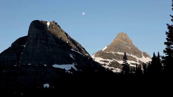 高清视频在蒙大拿州冰川国家公园的太阳路上拍摄森林和月亮覆盖着雪山
