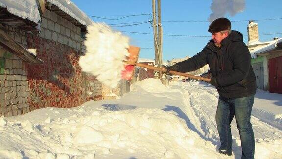 一名男子灵巧地用木铲清除通往车库的道路上的积雪
