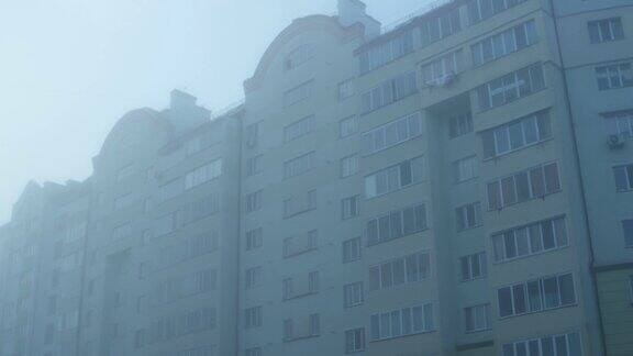 多层住宅楼在浓重的晨雾中背景