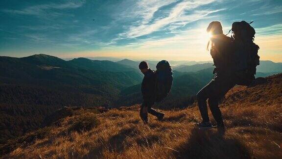 男人和女人在夕阳的背景下走在山上慢动作