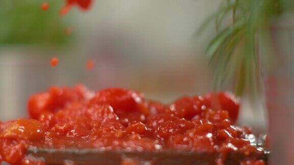 多汁的樱桃番茄块落入一个黑色盘子的酱汁中