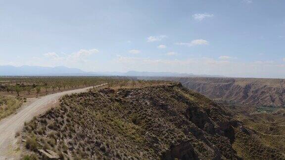 无人机在西班牙格拉纳达内华达山脉的蓝天中拍摄的GorafeDesiertodeloscolorado的干燥山谷和山脉在安达卢西亚有植被的西班牙沙漠峡谷跟踪在树上