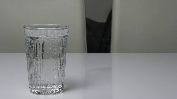 喝水的杯子放在白色的厨房桌子上矿泉水里有气泡杯子里盛满了饮用水