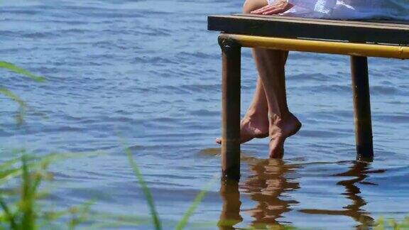 那个女孩坐在河边的一个木码头边上休息