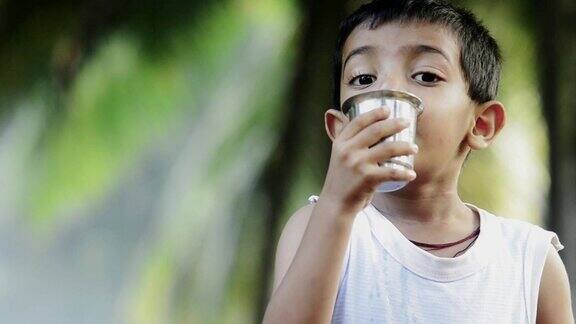 可怜的印度小男孩用钢玻璃喝水