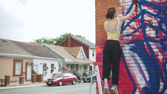 年轻女子在房子上画壁画