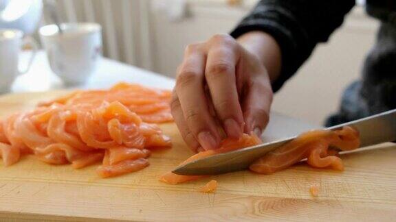 手工厨师用刀将生鲑鱼切在砧板上