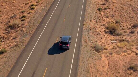 一辆黑色SUV行驶在沙漠中空旷的道路上
