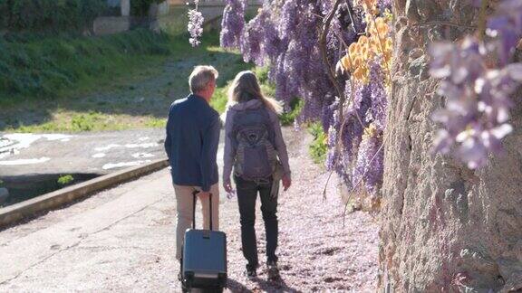 高年级男女走过紫藤花墙