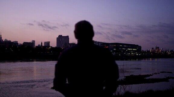 河畔美丽的日落城市的背景欣赏风景的男人