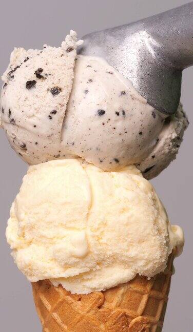 在灰色的背景上香草冰淇淋筒上有一勺饼干冰淇淋