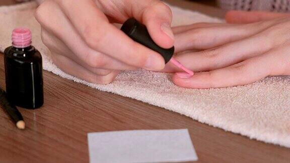 一位女士在指甲上涂上了第一层粉色虫胶特写镜头
