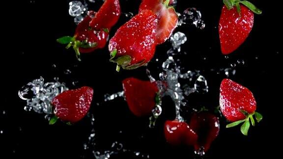 在黑色的背景上草莓随着水花飞溅而起